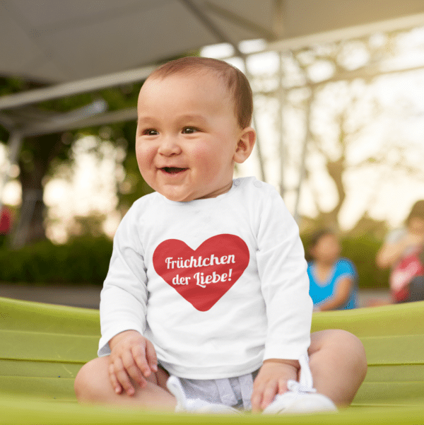 Ein Baby mit einem Body mit dem Druck Früchtchen der Liebe