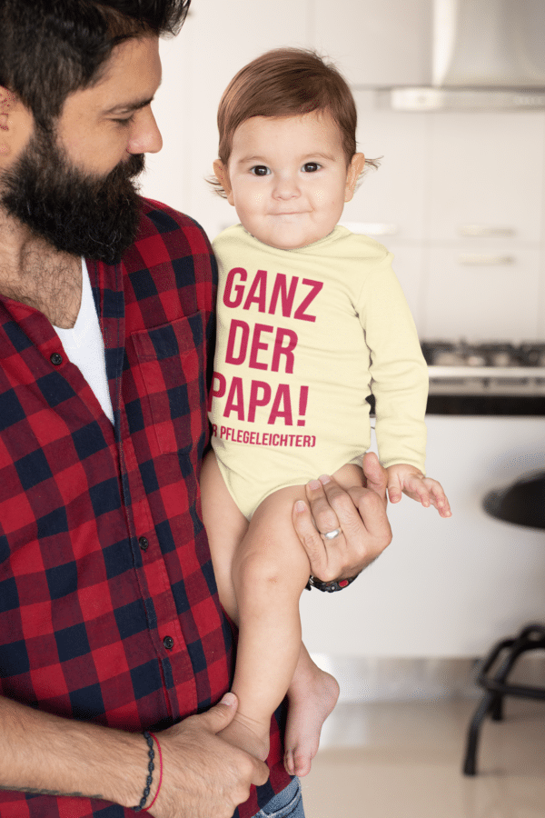 Ein Baby mit einem Body mit dem Druck Ganz der Papa