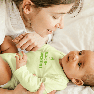 Ein Baby mit einem Body mit dem Druck Milchmädchen