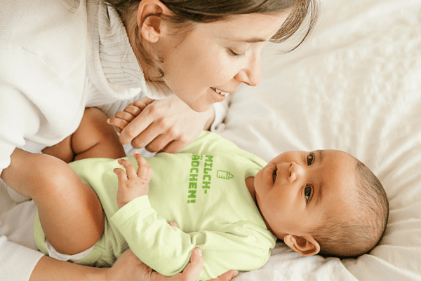 Ein Baby mit einem Body mit dem Druck Milchmädchen