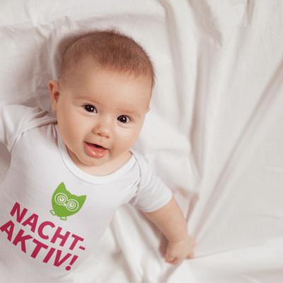 Ein Baby mit einem Body mit dem Druck Nachtaktiv